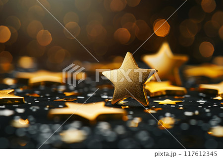 Golden stars and glitter on a dark surface with bokeh lights in the background 117612345