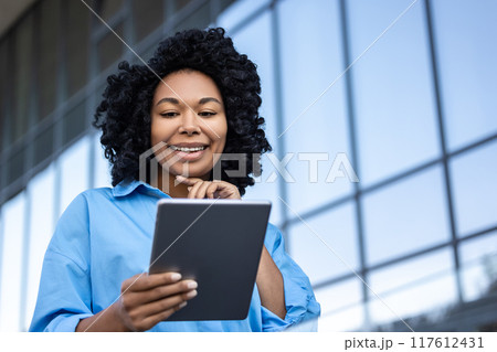 Waist up of a woman with tablet in hands working outdoors 117612431