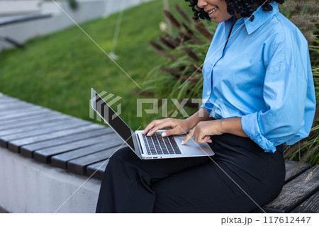 Close up of woman in blue shirt working on laptop Close up of woman in blue shirt working on laptop 117612447