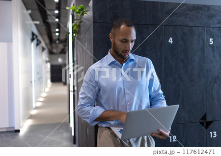 Confident businessman in office hall with laptop 117612471