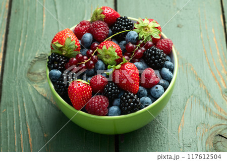 Mix of ripe colorful berries in bowl photography . Blueberry , strawberry , raspberry , blackberry and red currant . Top view 117612504