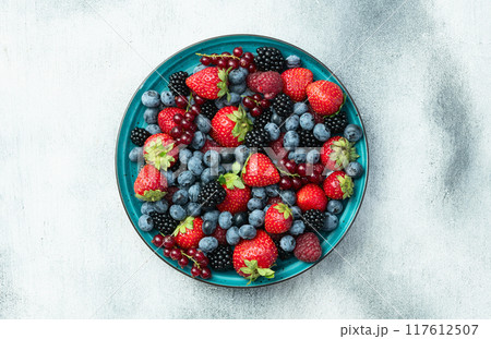 Mix of ripe colorful berries in bowl photography . Blueberry , strawberry , raspberry , blackberry and red currant . Top view 117612507
