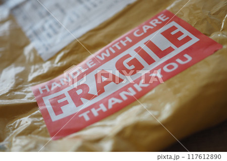 A cardboard box marked with a caution label for fragile goods handling during shipping 117612890