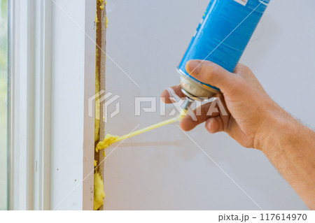 Construction foam is blown into gap between window wall by worker 117614970