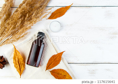 Autumn skin care concept. Bottle of pine essential oil on a white wooden background. Aromatherapy and eco-friendly cosmetics. Copy space. Autumn skin care concept. Bottle of pine essential oil on a white wooden background. Aromatherapy and eco-friendly cosmetics. Copy space. 117615641