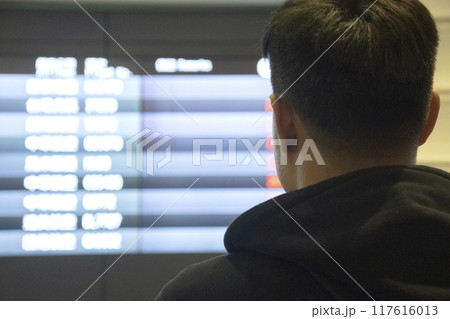 man checking his flight on the timetable display at the airport man checking his flight on the timetable display at the airport 117616013