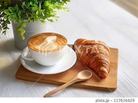 カッティングボードにのせたコーヒーとクロワッサン 117616829