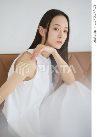 優しい光が心地良い窓際のソファに座りリラックスする女性 117617415