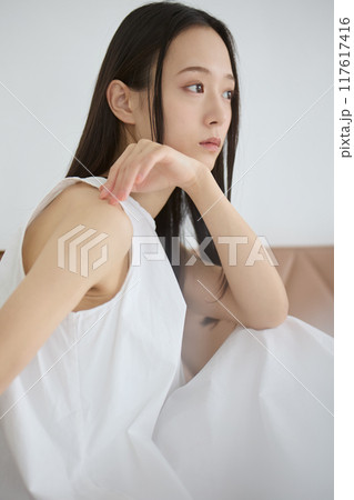 優しい光が心地良い窓際のソファに座りリラックスする女性 優しい光が心地良い窓際のソファに座りリラックスする女性 117617416