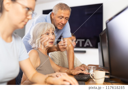 Friendly elderly computer course teacher helping woman learn computer Friendly elderly computer course teacher helping woman learn computer 117618285