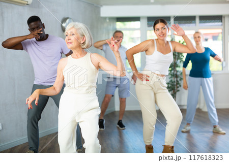 Men and women of different ages practicing Rock 'n' Roll dance in training hall 117618323