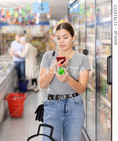 Woman purchaser scanning label of cool drink by phone 117618357