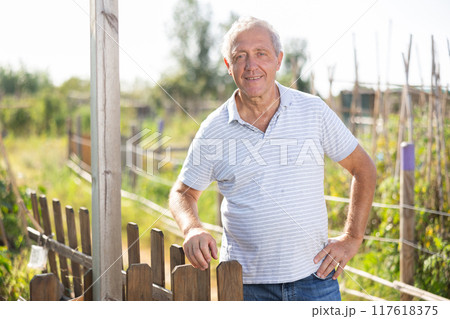 Portrait of an elderly owner of village farm with tools in his hands 117618375