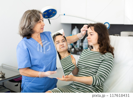 Experienced cosmetology doctor examines face a young woman patient Experienced cosmetology doctor examines face a young woman patient 117618431