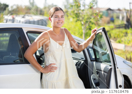 Young woman posing by car in garden Young woman posing by car in garden 117618476