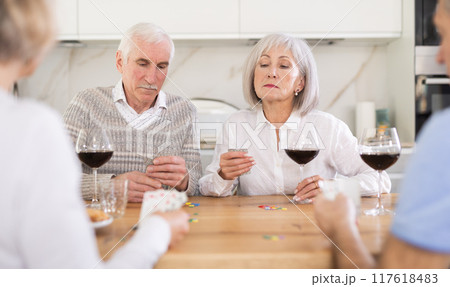 Two mature married couples playing card game poker 117618483