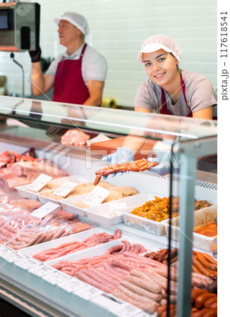 The saleswoman offers fresh baby chorizo sausages at the butcher shop The saleswoman offers fresh baby chorizo sausages at the butcher shop 117618541