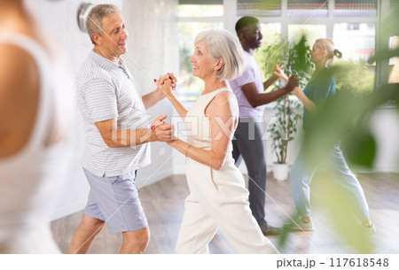 Mature men and women practicing Ballroom dances in training room 117618548