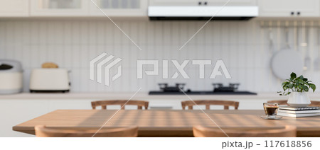 A space for displaying products on a wooden dining table in a contemporary white kitchen. 117618856