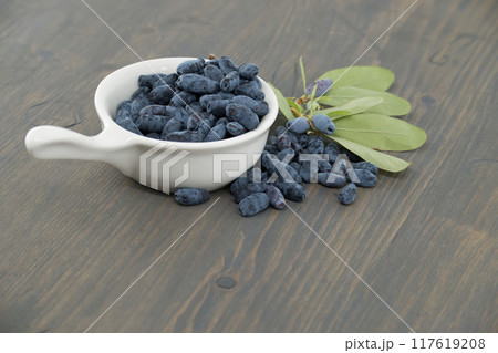 White bowl filled with Honeyberry haskap berries on wooden table White bowl filled with Honeyberry haskap berries on wooden table 117619208