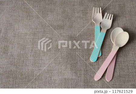 Wooden colorful spoons and forks on mat under plate. Disposable eco-friendly tableware. Food and snacking. Background for design. Wooden colorful spoons and forks on mat under plate. Disposable eco-friendly tableware. Food and snacking. Background for design. 117621529