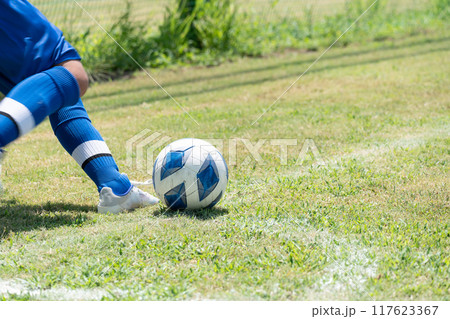 サッカーの試合でコーナーキックを蹴る小学生の男の子 117623367