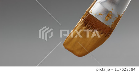 Brush with gold paint on a gray background Brush with gold paint on a gray background 117625584