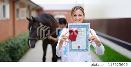 Happy woman vet doctor holding a horse certificate 117625606