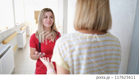 A doctor in listens to a woman in the hospital corridor 117625611