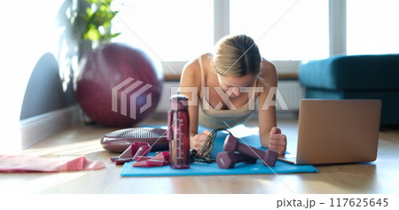 A woman over 30 on the floor does a plank exercise 117625645