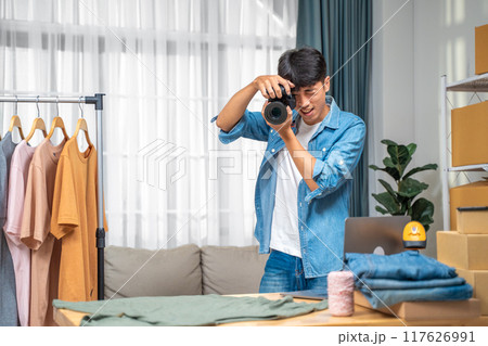 Young online seller man taking pictures of his shirt product to use on his website and online review at his home studio 117626991