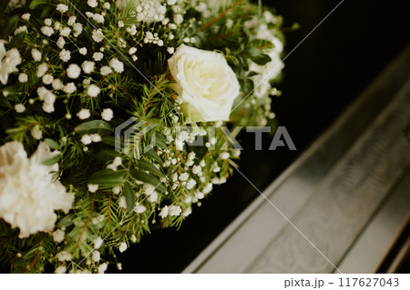 Medium close up of white roses with fur tree on wooden coffin Medium close up of white roses with fur tree on wooden coffin 117627043