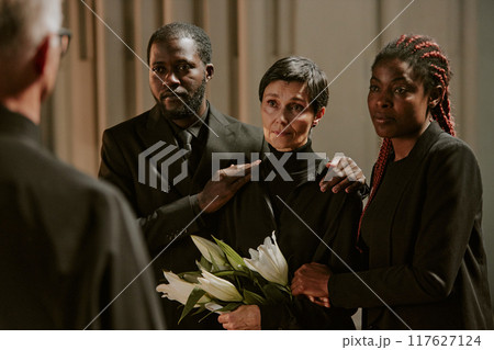 Biracial family listening to pastors words in church before burial ceremony 117627124