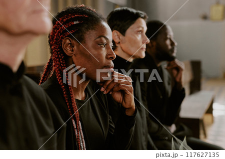 Mournful African American woman dressed in total black with eyes full of tears in church during burial service 117627135