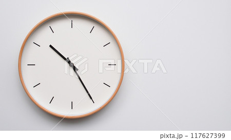 Minimalist wooden Wall Clock on White Wooden Surface with Space for Text. Time Set at 10.25/22.25 117627399