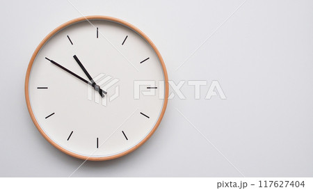 Minimalist wooden Wall Clock on White Wooden Surface with Space for Text. Time Set at 22.50/10.50 Minimalist wooden Wall Clock on White Wooden Surface with Space for Text. Time Set at 22.50/10.50 117627404
