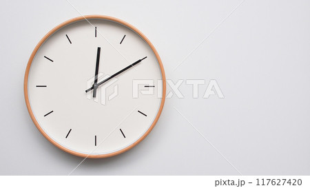 Minimalist wooden Wall Clock on White Wooden Surface with Space for Text. Time Set at 12.10/00.10 117627420