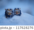 雪の中で寒そうなシーサーの置物 117628276