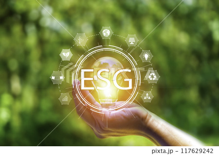 Net zero 2050 ESG concept, Hand with green world, wind energy system icon on blurred green leaf background. wind energy for green environment. Businessman background with energy icons around. 117629242