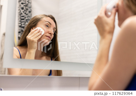 Smiling woman using cream stick to smooth out wrinkles on her face or like sun protection cream stick. 117629364