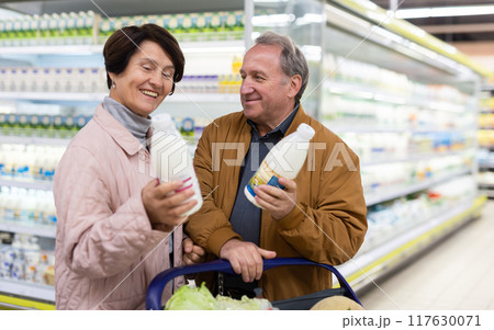 Mature couple choosing jug of milk in dairy department in grocery store Mature couple choosing jug of milk in dairy department in grocery store 117630071