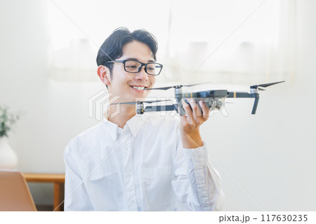 自宅でドローンの点検整備をする男性 117630235