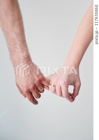 Close up of man's and woman's hands taking each other for little fingers. Married couple holding hands. Concept of love, intimacy, support, and trust. 117630868
