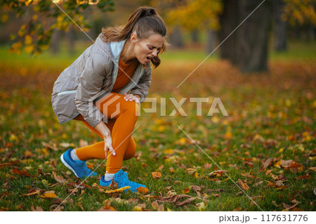 sad modern woman in fitness clothes in park 117631776