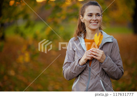 happy trendy woman in fitness clothes in park 117631777