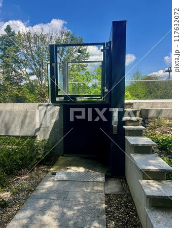 Entrance to a public elevator for people with disabilities with a blue glass door and steps. Entrance to a public elevator for people with disabilities with a blue glass door and steps. 117632072
