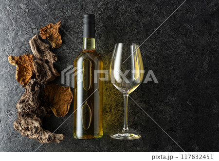 Bottle of white wine on a black stone background. 117632451
