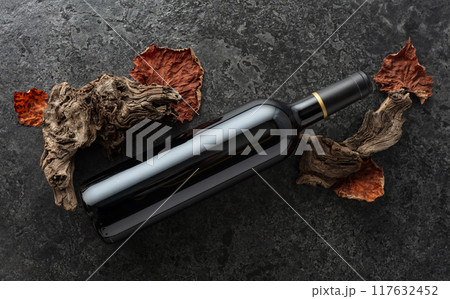 Bottle of red wine on a black stone background. 117632452