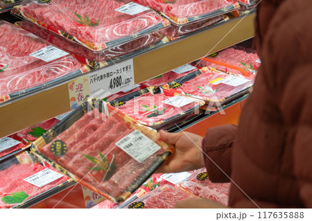 正月用の肉をスーパーで手に取る 117635888