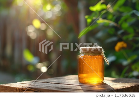 Honey in a glass jar on a wooden table in the garden 117636019